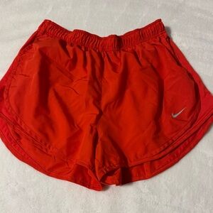 Red-orange Nike brand running shorts with attached brief.